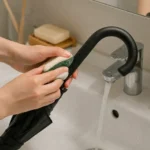 우산 손잡이 끈적임 해결-우산 손잡이 세탁비누와 수세미로 닦는 장면